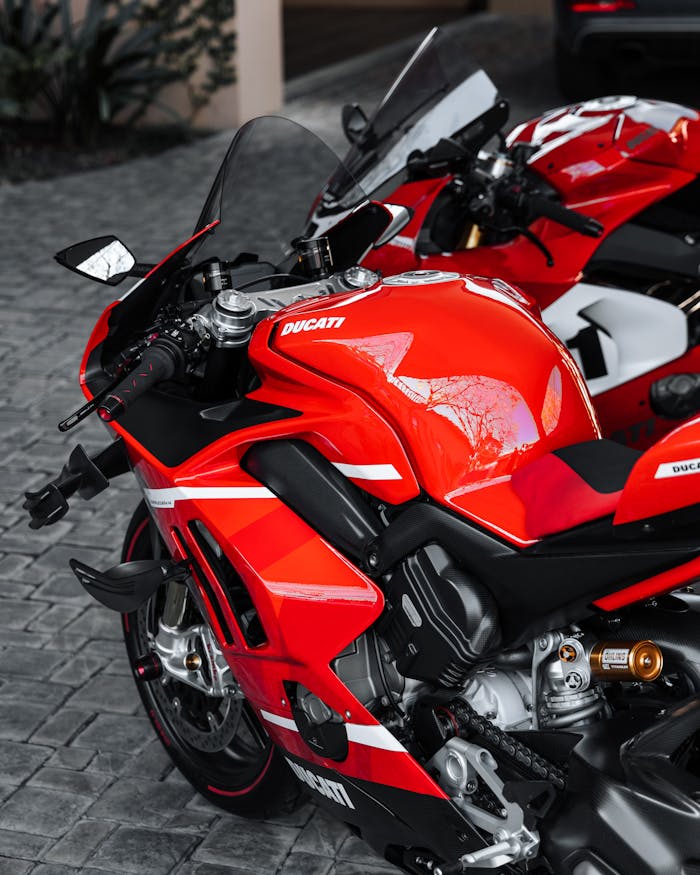 about-us Vibrant red Ducati motorbike parked on cobblestone street, showcasing sleek design and speed.